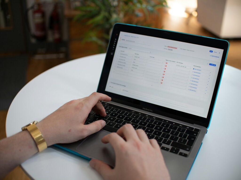 Hands typing on a laptop showing a spreadsheet