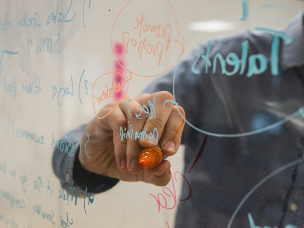 Person drawing a diagram on a glass whiteboard