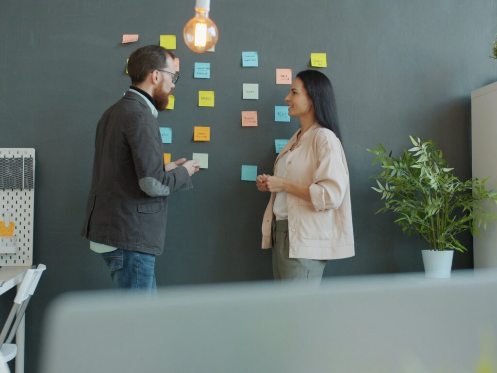 Two colleagues planning with sticky notes on a wall