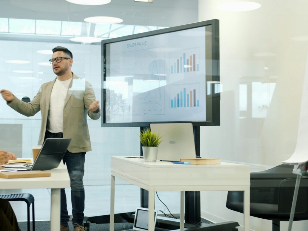Man presenting data on a large screen to colleagues